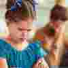 Little girl in a blue dress looking sad in front of her parents who are arguing