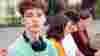Four teenagers are sitting together. A teenage boy looks into the camera
