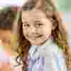 Primary aged girl with curly hair smiles into the camera