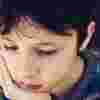 Boy wearing a patterned jumper resting his chin on his fist