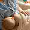 Baby wrapped in beige blanket breastfeeding